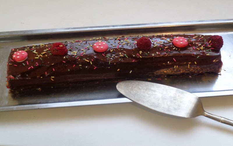 Bûche de Noël au chocolat maison décorée de sucre glace, framboises et meringues