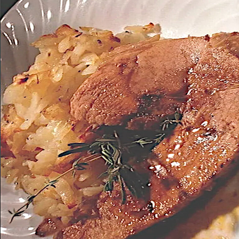 Plat de rouelle de porc fondante au miel et pommes de terre dorées, garni de thym et ail