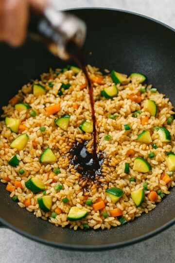 Étape 2 : sauce soja versée sur riz brûlant dans un wok