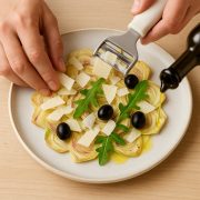 Dressage du carpaccio d'artichauts au parmesan : lamelles en éventail, copeaux de fromage, roquette, olives et filet d'huile d'olive