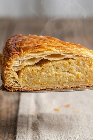 Gros plan sur une part de galette sans gluten montrant le feuilletage croustillant et une frangipane onctueuse