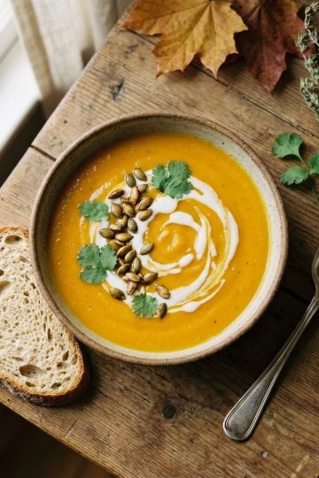 Bol de velouté de butternut au lait de coco onctueux décoré de graines de courge et coriandre