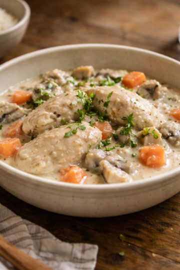 Blanquette de poulet maison servie en bol avec sauce blanche crémeuse, carottes et champignons, ambiance cuisine familiale