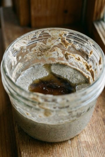 Levain naturel affamé dans un bocal : surface plate et retombée avec présence d'une couche de liquide gris (hooch)