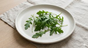 Lit de roquette fraîche sur assiette blanche en céramique, style minimaliste, base de la salade burrata fraises