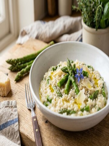 Risotto crémeux aux asperges vertes en assiette creuse blanche, copeaux de parmesan et fleur de bourrache
