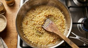 Riz basmati nacré dans l'huile chaude avec oignon doré, étape clé de la recette
