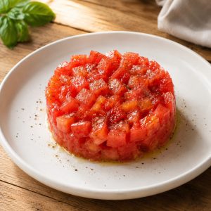 Dôme de tartare de tomates dressé en cercle sur une assiette blanchepng