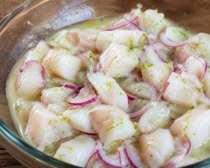 Dés de poisson en train de mariner dans le jus de citron vert et le zeste de combava