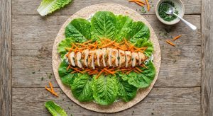 Tortilla garnie avec salade, carotte râpée et poulet avant de rouler le wrap froid
