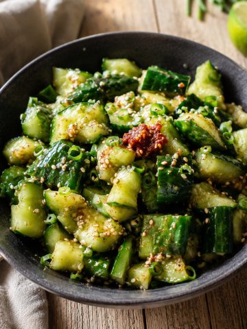 une salade de concombre créole servie en dôme dans un bol sombre, avec sésame et piment