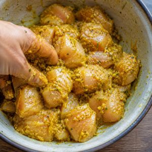 Cubes de poulet en train de mariner dans la pâte d'épices jaune au safran peï