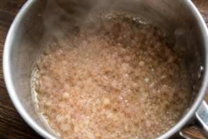 Réduction d'échalote au vin blanc presque à sec dans une casserole inox, base du beurre blancpng