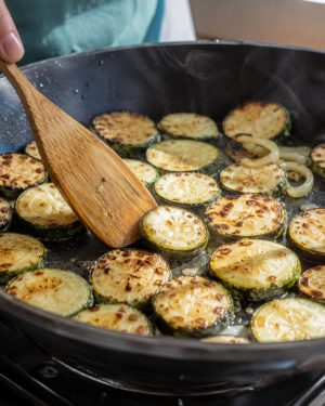 Rondelles de courgettes en train de dorer à feu vif dans une poêle