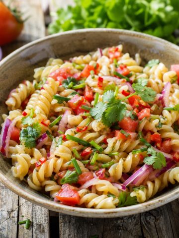 Salade de pâtes façon rougail servie dans un bol, parsemée de coriandre fraîche