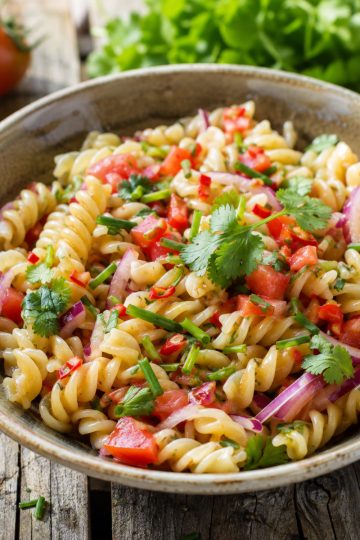 Salade de pâtes façon rougail servie dans un bol, parsemée de coriandre fraîche