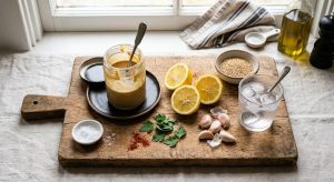 Ingrédients de la sauce tahini : tahiné, citrons, ail et eau glacée sur une planche