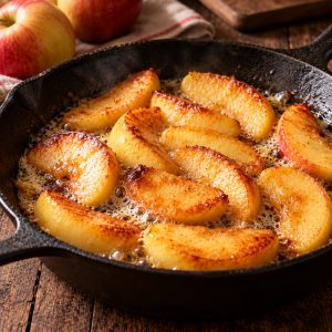 Lamelles de pommes dorées au beurre dans une poêle en fonte