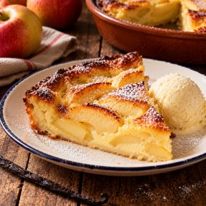 Part de clafoutis aux pommes tiède avec une boule de glace vanille