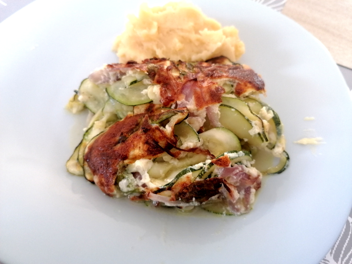 Part de gratin de courgette curry-basilic servie tiède dans une assiette
