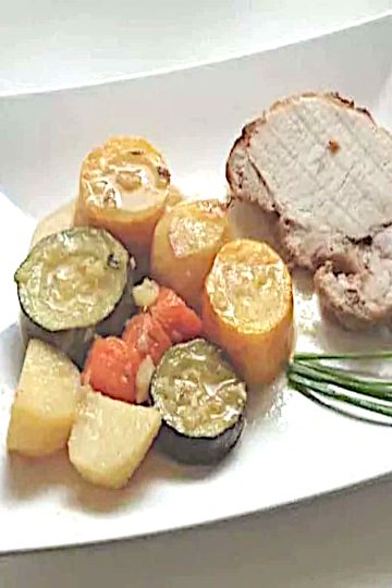 Rôti de porc au four aux légumes de saison, tranché dans sa cocotte avec courgettes, carottes et pommes de terre