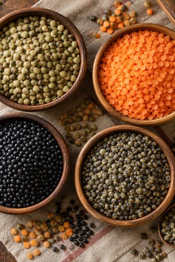 Variétés de lentilles dans des bols en bois : vertes, corail, noires et du Puy